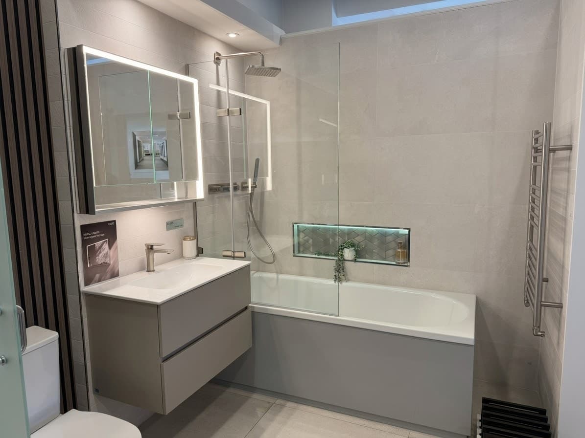 A complete bath and shower room set in the showroom, with a fitted vanity, illuminated mirror cabinet and heated towel rail
